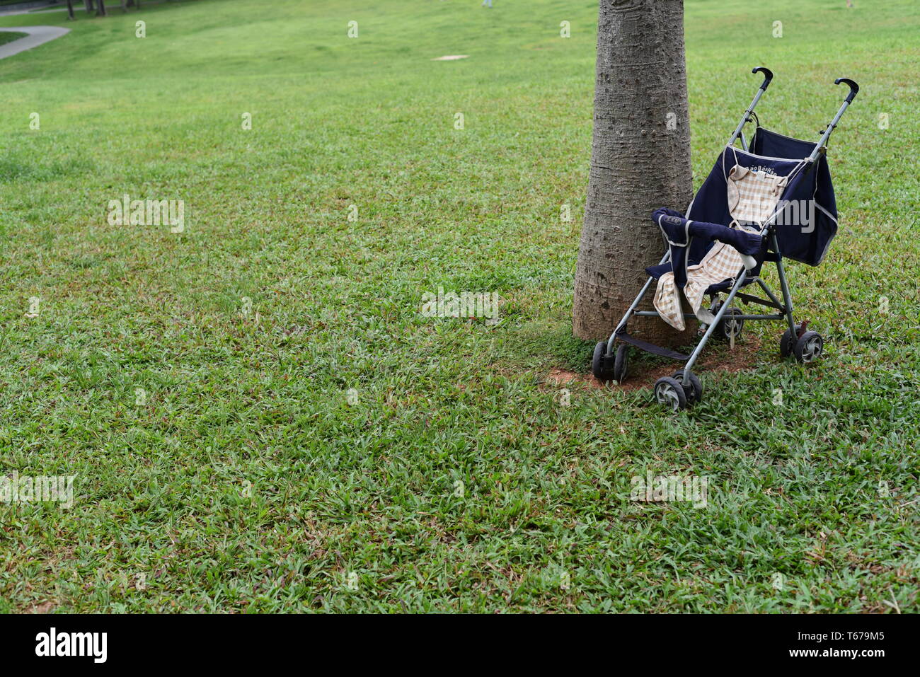 In questa foto si è focalizzato su un singolo servizio baby carrello posto vicino ad un albero in erba, con un pulito e sfondo vuoto in un parco a Shenzhen, Cina. Foto Stock