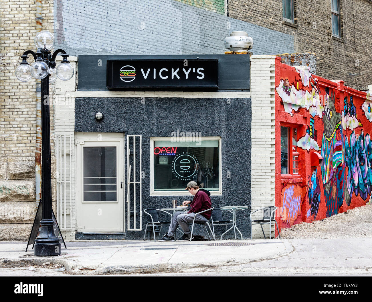 Uomo di mangiare da soli in un burger comune, Exchange District, Winnipeg, Manitoba, Canada. Foto Stock