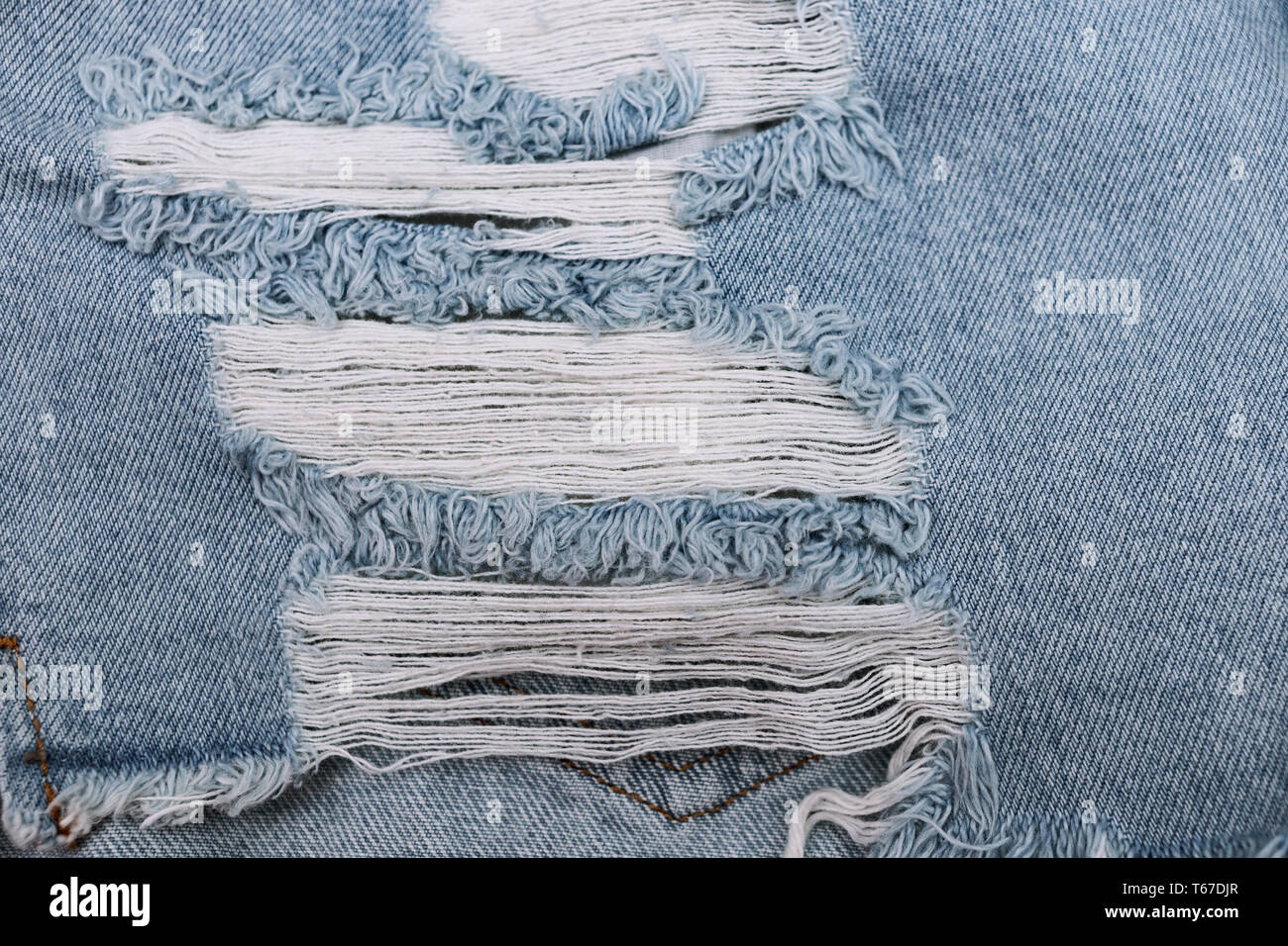 Foro e filettature sul Jeans Denim. Strappato distrutto jeans blu sullo sfondo. Close up blu jean texture. Foto Stock