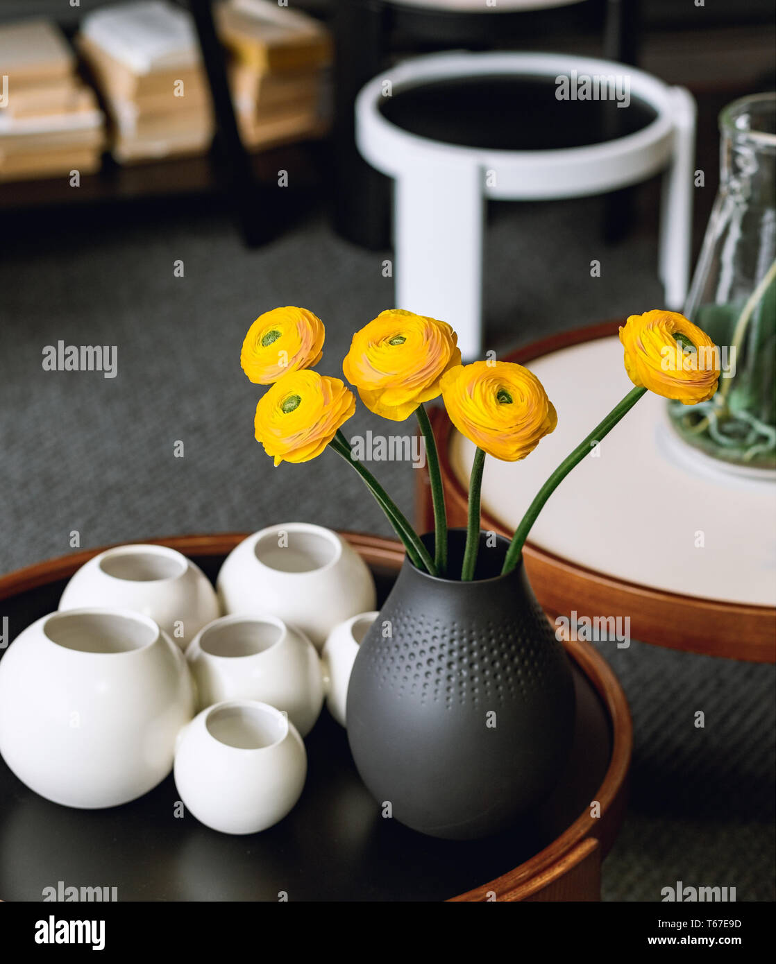 Bouquet di roselline (Ranunculus asiaticus) in un vaso nero. Fiori di colore giallo all'interno. Foto Stock