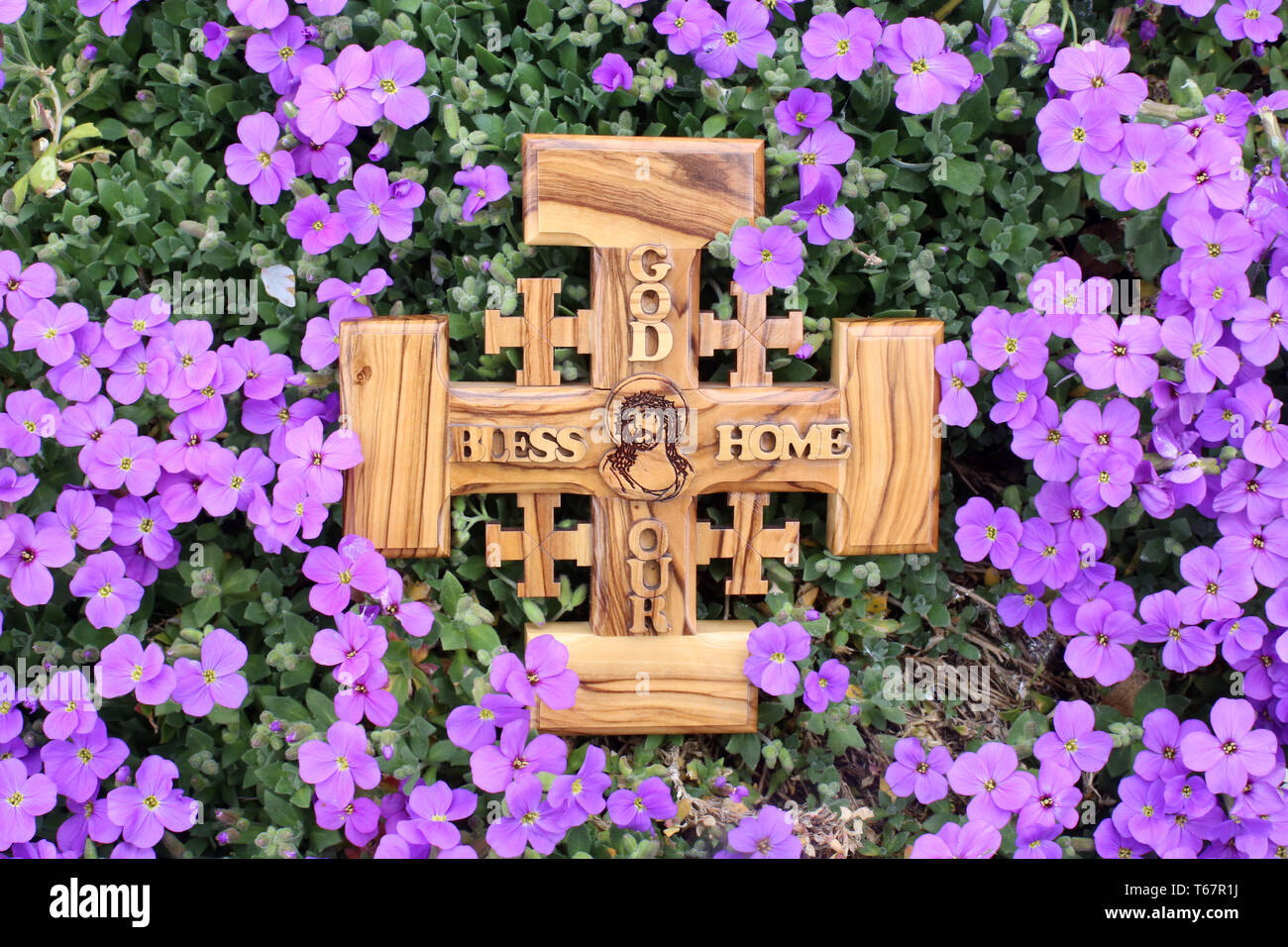 Croix de Jérusalem en bois d'olivier représentant Jésus-Christ sur onu parterre de violettes. Foto Stock