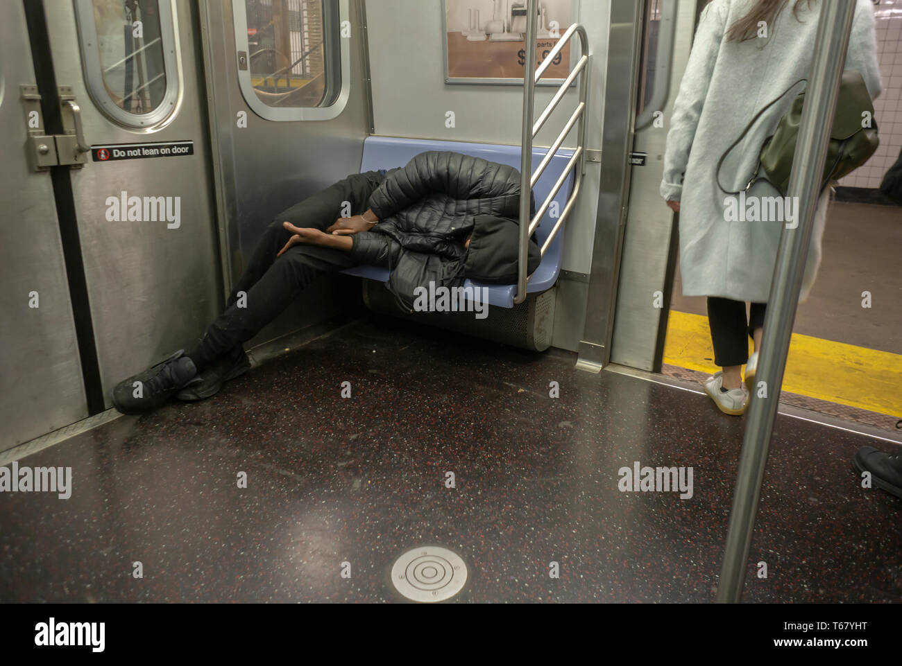 Un senzatetto individuo è visto dormendo distesa su un sedile sulla metropolitana di New York il giovedì 18 aprile, 2019. (Â© Richard B. Levine) Foto Stock