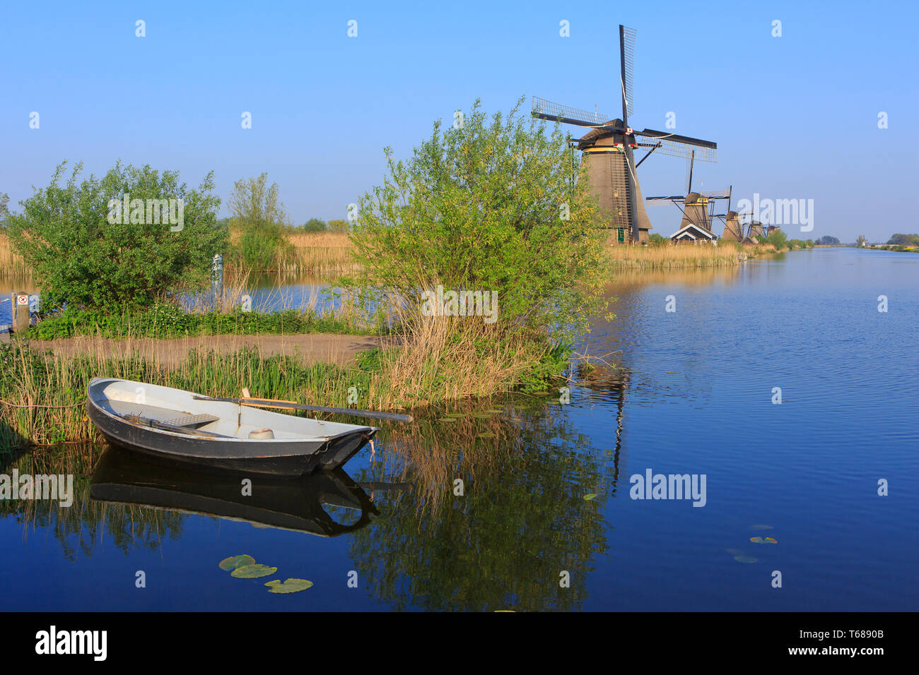 Una piccola barca ormeggiata lungo il XVIII secolo i mulini a vento in un sito Patrimonio Mondiale dell'UNESCO in Kinderdijk, Paesi Bassi Foto Stock