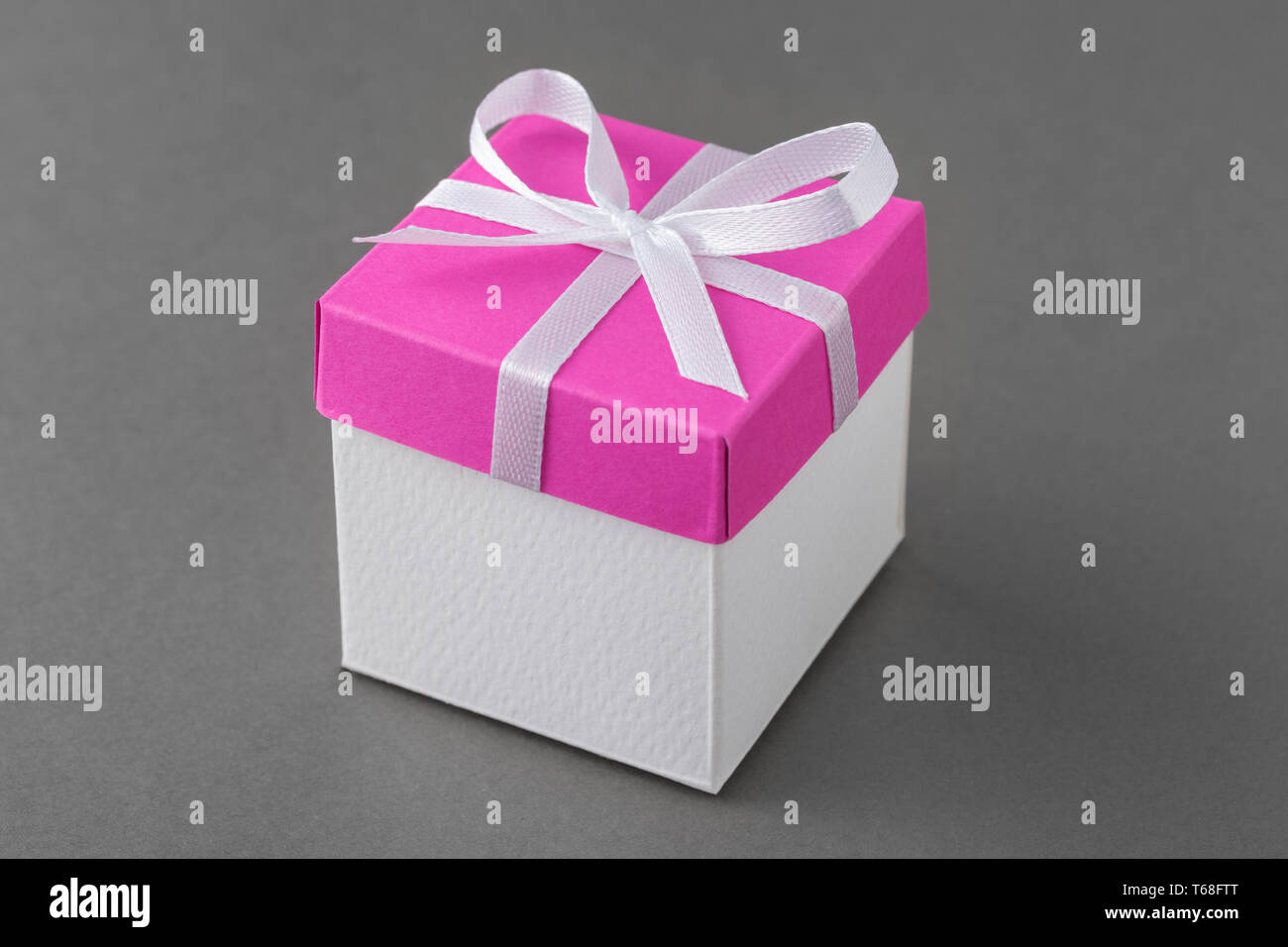 Confezione regalo con coperchio rosa e fiocco di seta su sfondo grigio. Foto Stock