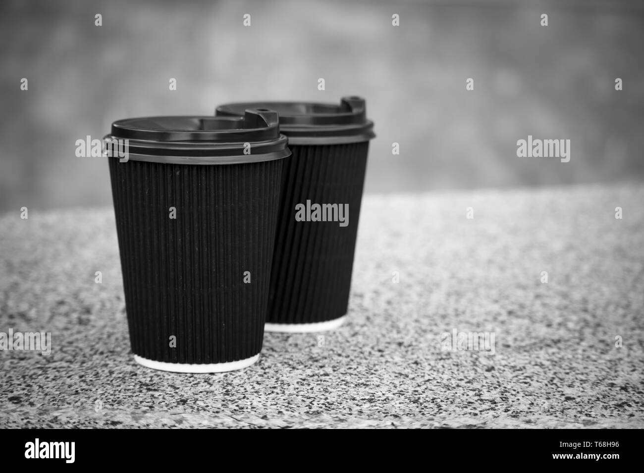 Due neri monouso di tazze di caffè con i coperchi sono in piedi sul parapetto di pietra, il resto e una passeggiata per la città, lo sfondo o il concetto Foto Stock