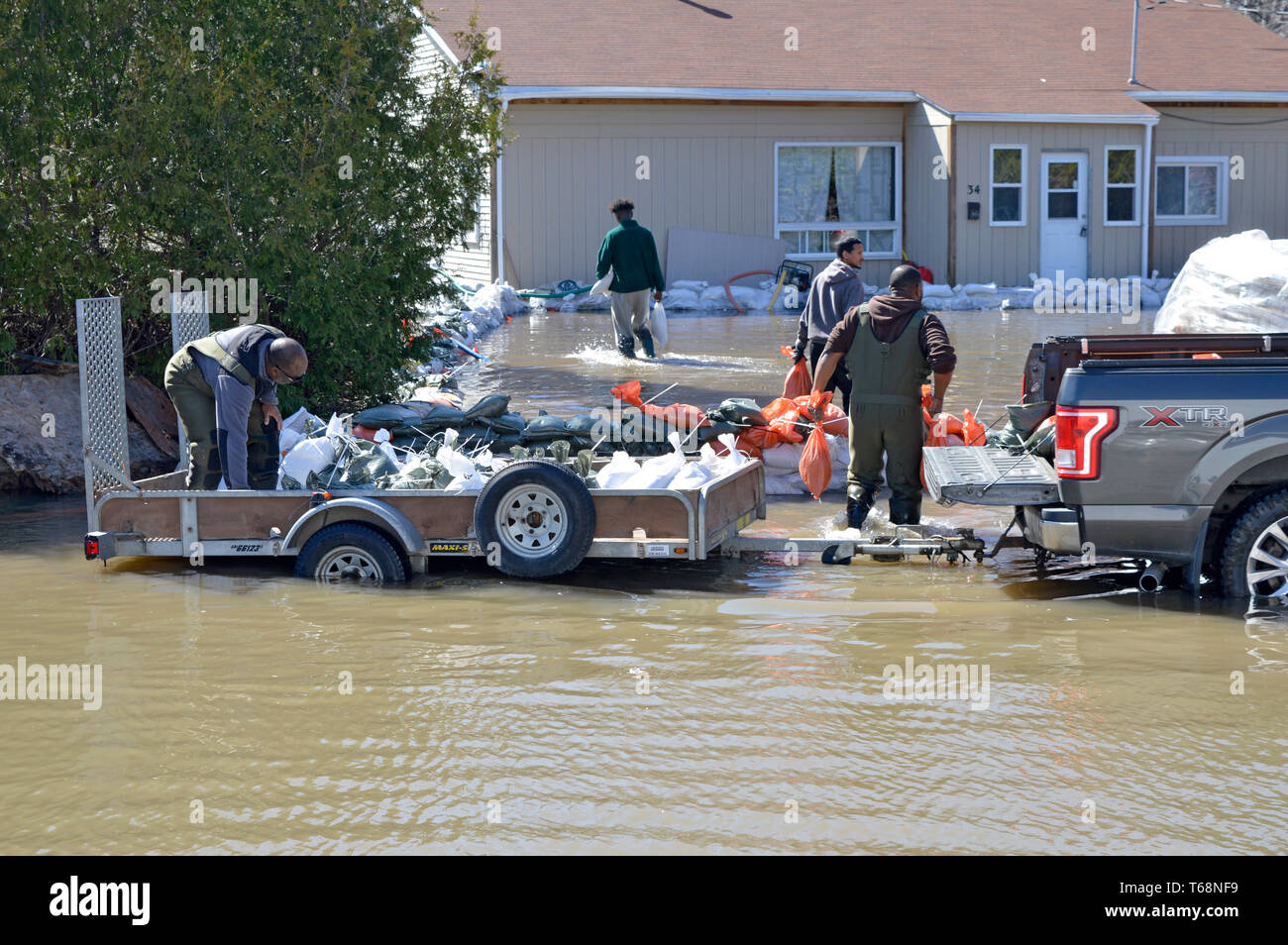 I volontari aiutano il carico e lo scarico di sacchi di sabbia per proteggere una casa in aumento le acque di esondazione in Gatineau (vicino a Ottawa) Canada, durante la primavera le inondazioni del 2019. Foto Stock