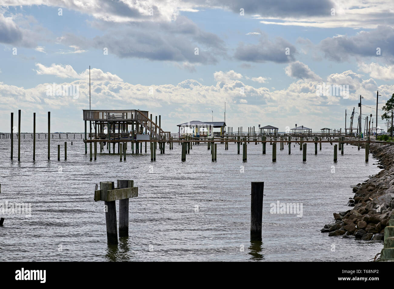Dock in legno di pontili e pilings lungo la riva di Mobile Bay sulla costa del Golfo, vicino Coden Alabama, Stati Uniti d'America. Foto Stock
