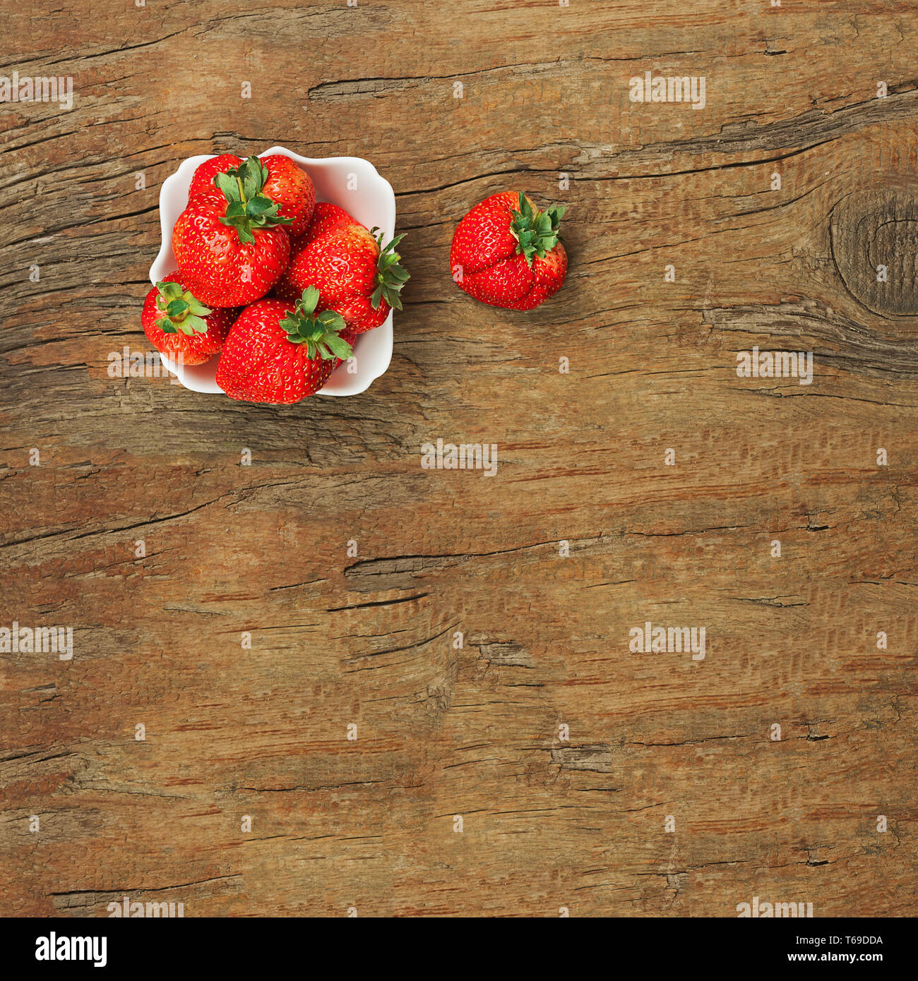 Fresche fragole mature nella ciotola bianco su sfondo di legno. Foto Stock