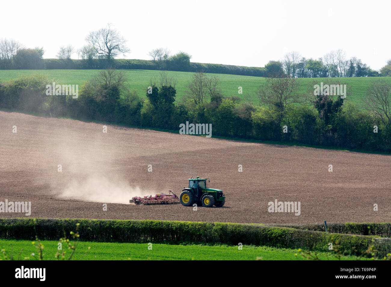 Un trattore John Deere straziante un campo, Warwickshire, Regno Unito Foto Stock