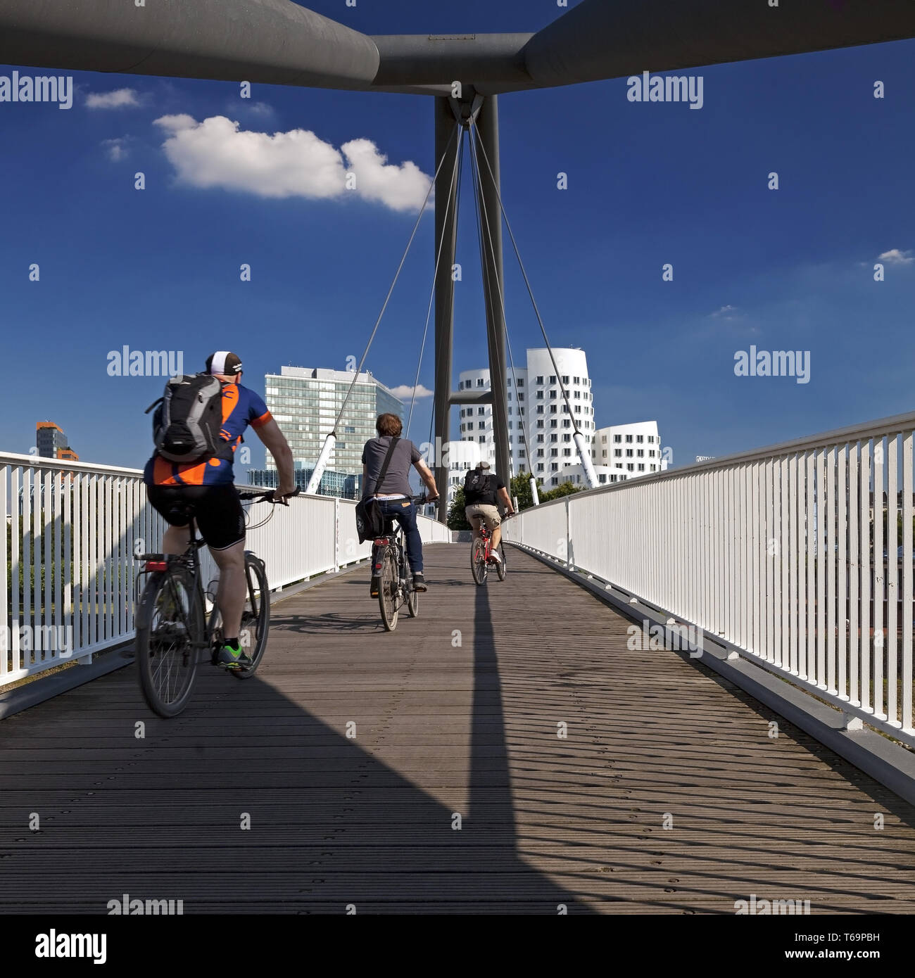 Ciclista sul Ponte del porto con la Torre sul Reno e Neuer Zollhof, Duesseldorf, Germania Foto Stock