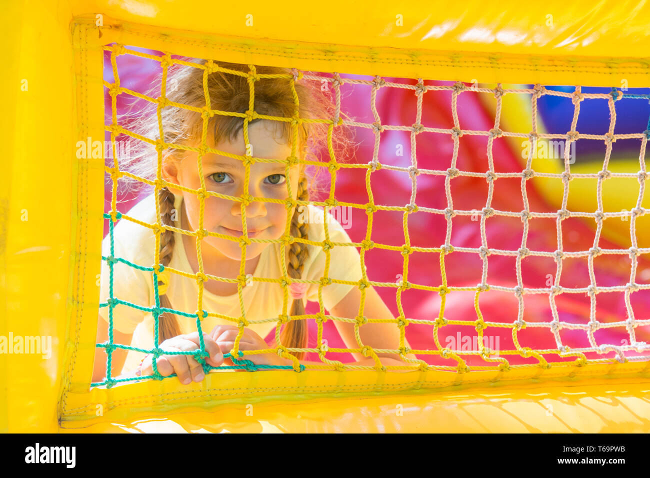 Cinque anni di ragazza è alla ricerca attraverso una maglia trampolino gonfiabile di Foto Stock