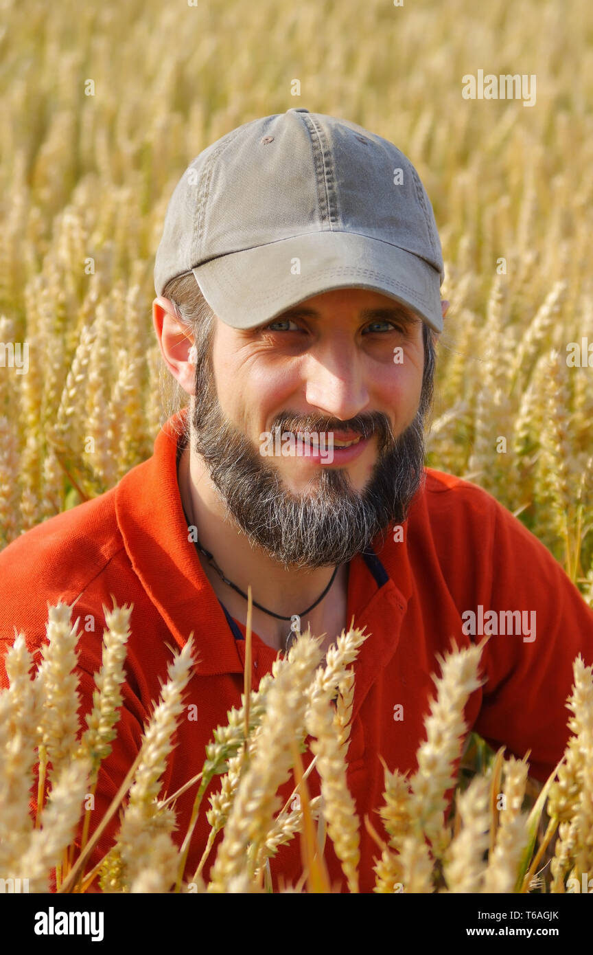 Uomo Barbuto seduto in un campo di grano sulla giornata di sole Foto Stock