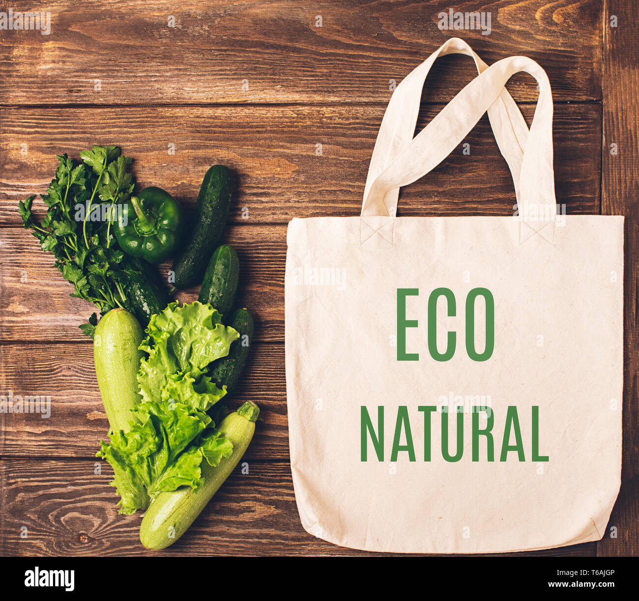 Il cotone shopping bag con la frase ECO naturali e freschi di verdura verde sullo sfondo di legno. Concetto di eco. Schema piatto. Foto Stock