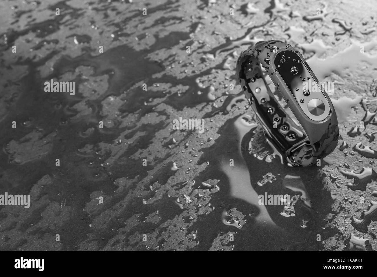 Wet braccialetto di fitness, fitness tracker su un nero ardesia sfondo con gocce di acqua Foto Stock