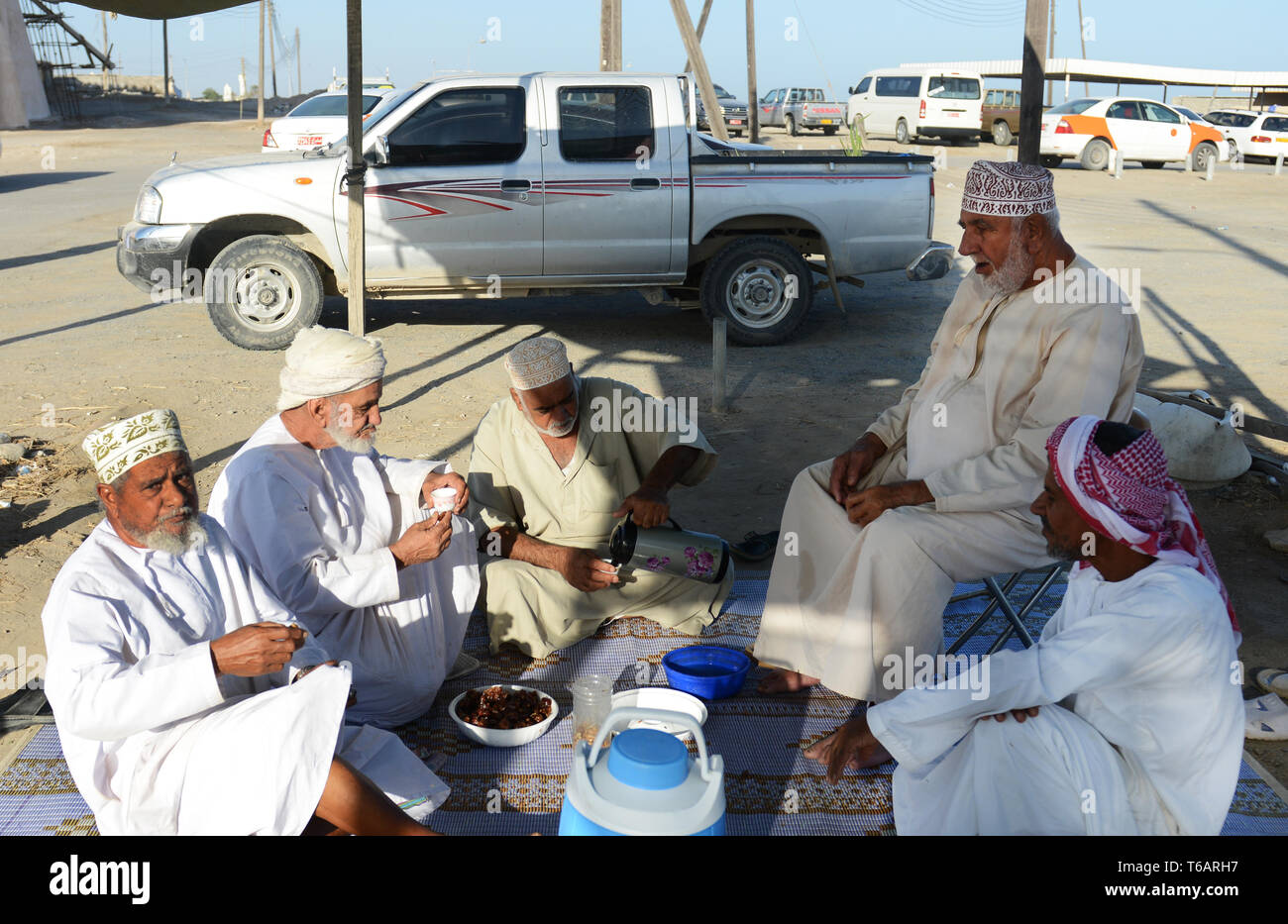 Omani uomini avente un tea break a til Mattina mercato del pesce nella città costiera di Barka, Oman. Foto Stock