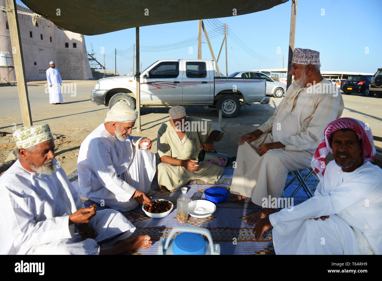 Omani uomini avente un tea break a til Mattina mercato del pesce nella città costiera di Barka, Oman. Foto Stock
