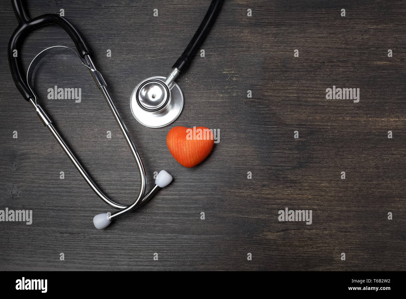 Health care concetto. Uno stetoscopio vicino a forma di cuore in legno scuro con sfondo spazio copia Foto Stock