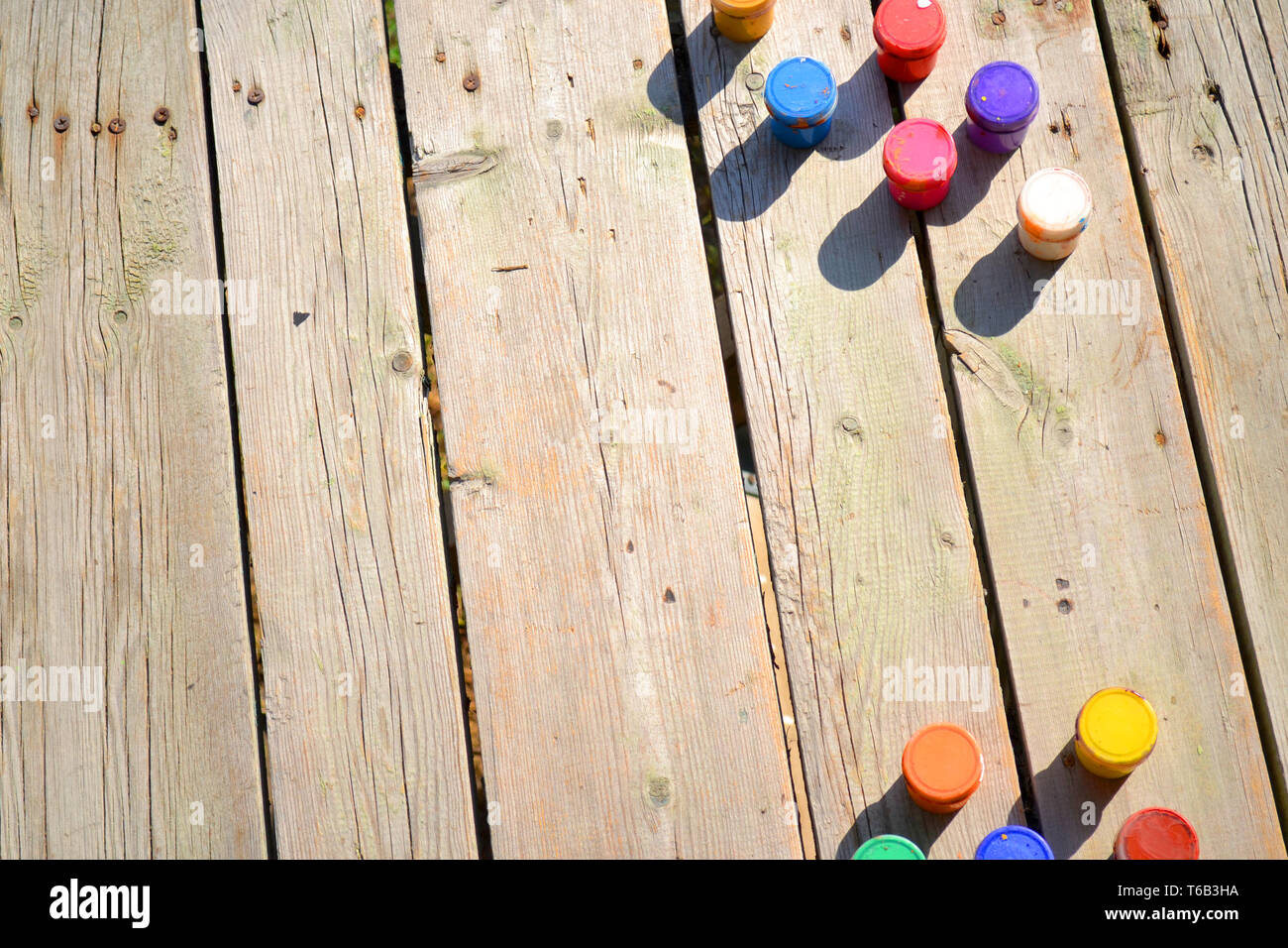 Sfondo di legno e piccoli barattoli di vernice gouache vista superiore in una giornata di sole. Sfondo, spazio per il testo Foto Stock