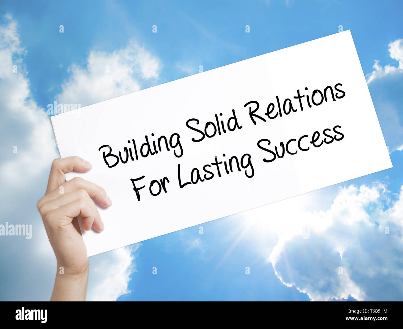 Costruire relazioni solide per un duraturo successo segno su carta bianca. Man mano che tiene la carta con testo. Isolato su sfondo cielo Foto Stock