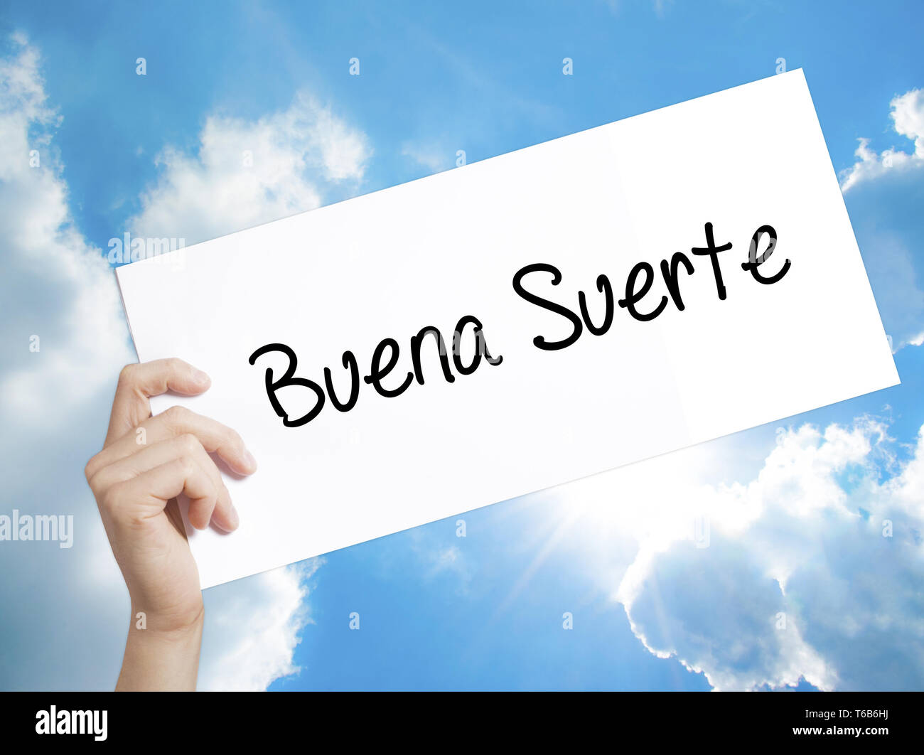 Buena Suerte( buona fortuna in spagnolo) firmare su carta bianca. Man mano che tiene la carta con testo. Isolato su sfondo cielo Foto Stock