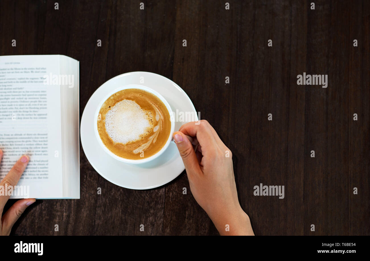 Ragazza avente il caffè al bar e la lettura di un libro Foto Stock