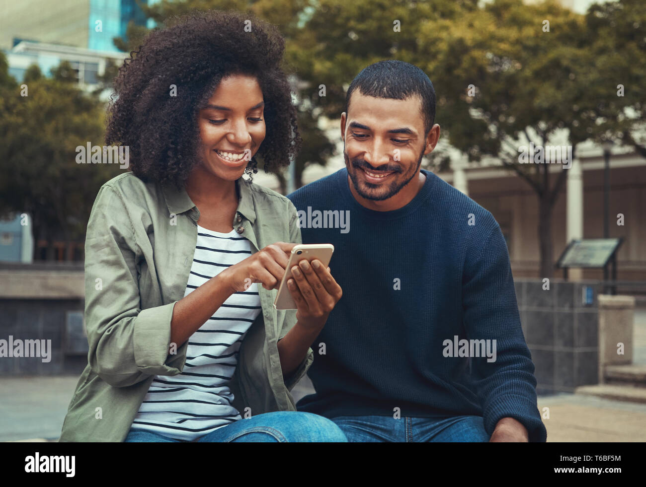 Uomo che guarda la sua ragazza utilizzando il telefono cellulare Foto Stock
