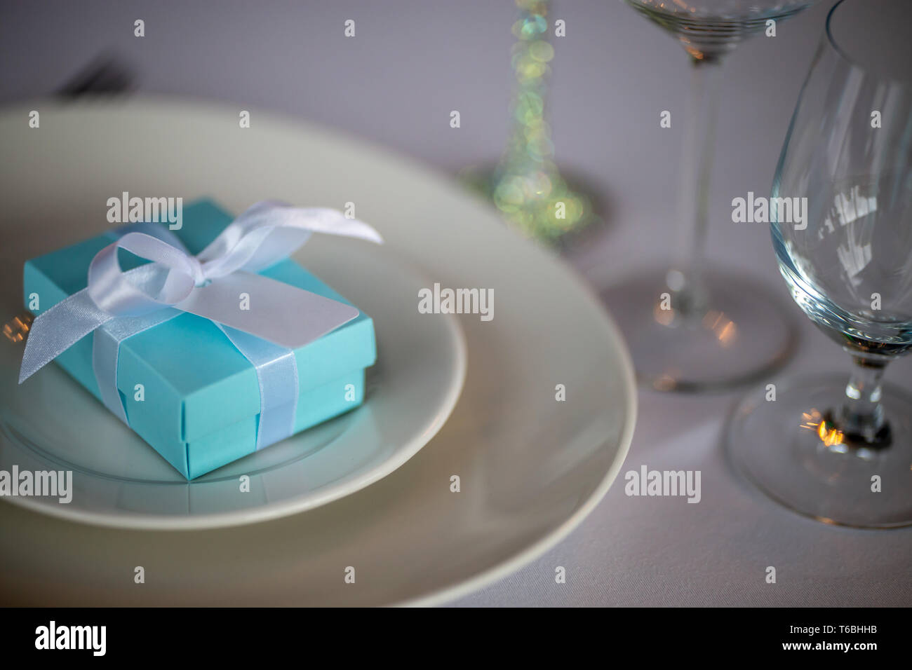 Festosa messa in tavola con fatti a mano scatola regalo sulla piastra. Luce blu a mano confezione regalo nella piastra sulla tabella di nozze. Foto Stock