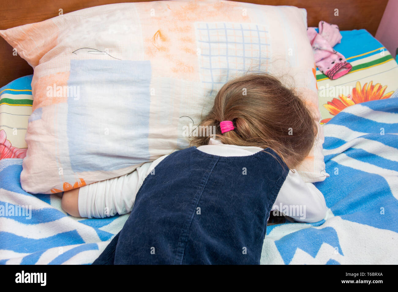 Cinque anni di ragazza grida con il suo volto sepolto nel cuscino Foto Stock