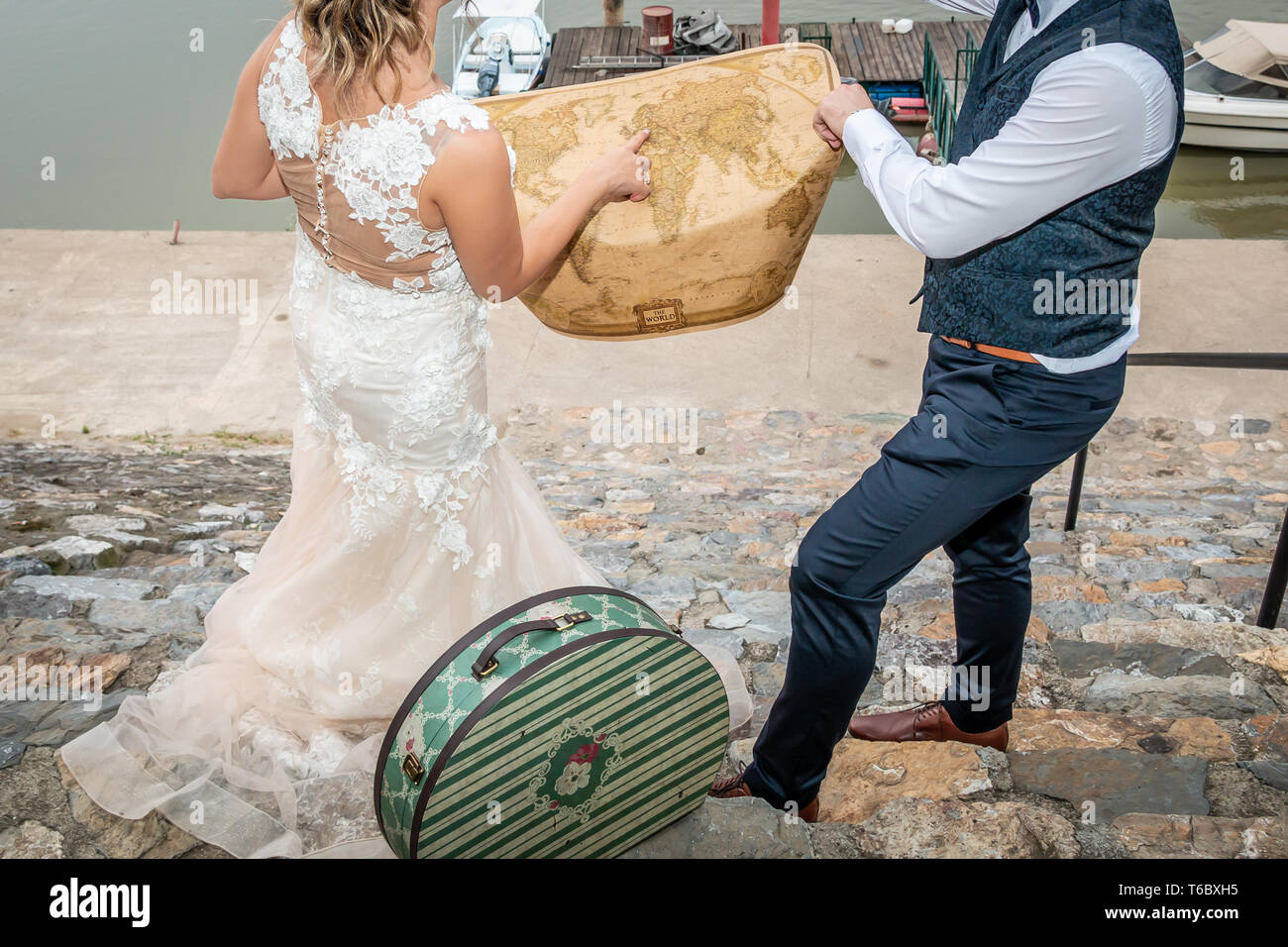 Sposa e lo sposo ad esplorare una mappa del mondo e la ricerca di un posto perfetto per una luna di miele. Destinazione di viaggio concetto. Foto Stock