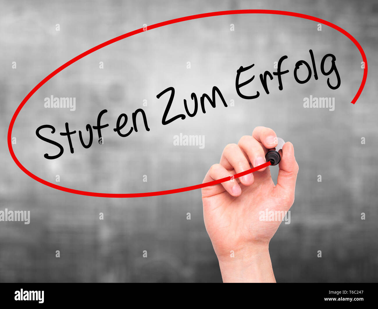 Man mano che scrive Stufen Zum Erfolg (Passi per il successo in tedesco) con pennarello nero su schermo visivo Foto Stock