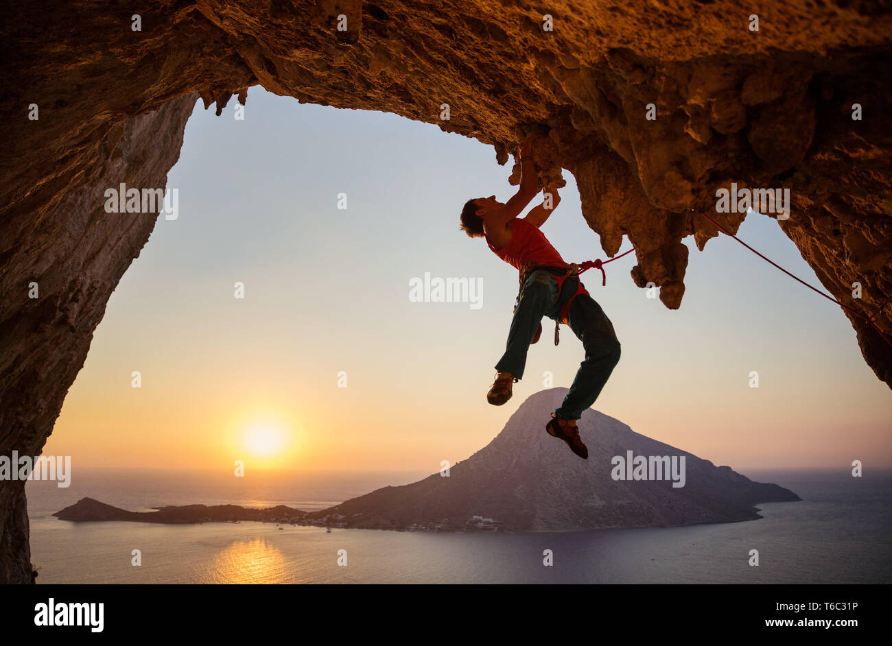 Maschio di rocciatore sull impegnativo percorso sulla rupe in grotta al tramonto Foto Stock