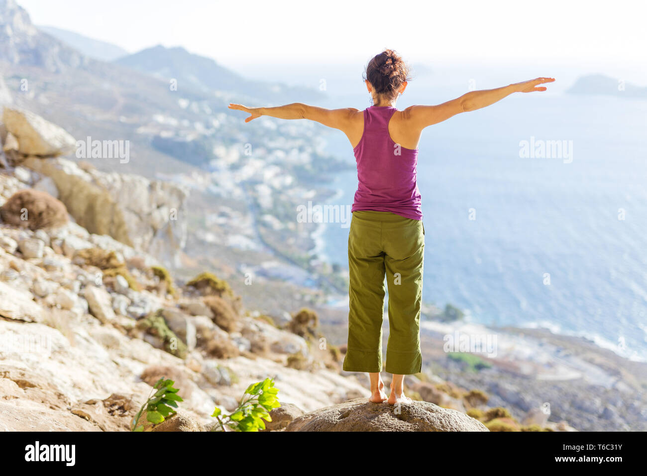 Giovane donna caucasica la pratica dello yoga o di lavoro permanente, mentre sulla scogliera sul mare Foto Stock
