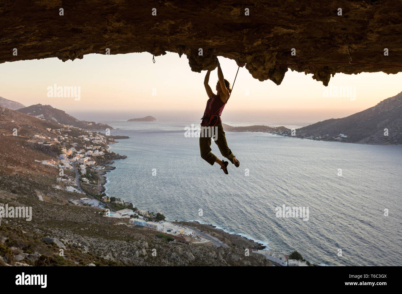 Femmina di rocciatore sul percorso impegnativo in grotta al tramonto, Kalymnos, Grecia Foto Stock