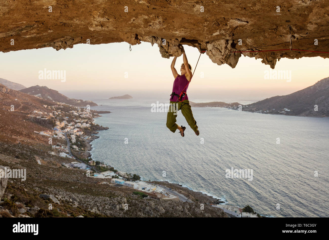 Femmina di rocciatore sul percorso impegnativo in grotta al tramonto, Kalymnos, Grecia Foto Stock