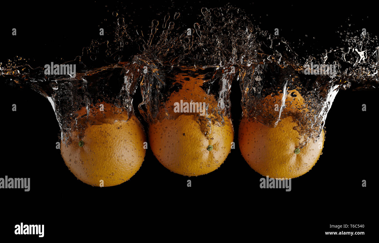 Gli spruzzi di frutta su acqua. Frutta fresca arancione essendo scattato come hanno sommerso sotto acqua su sfondo nero Foto Stock