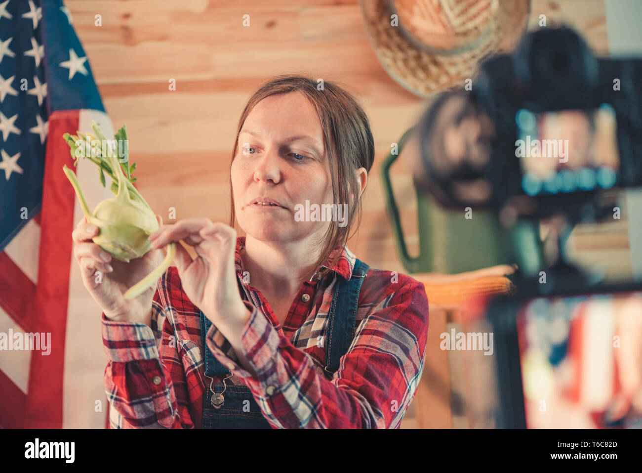 L'agricoltore femmina rendendo i social media vlog video sul lavoro agricolo stagionale e attività agricola, Donna vestita come lavoratore agricolo interessato nella parte anteriore della fotocamera t Foto Stock