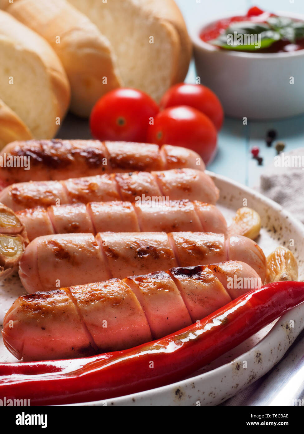 Vista ravvicinata del pollo salsicce fatte in casa con ciambelle di pane. Salsicce alla griglia e verdure grigliate in craft piastra alla moda. Home hotdog. Verticale. Foto Stock