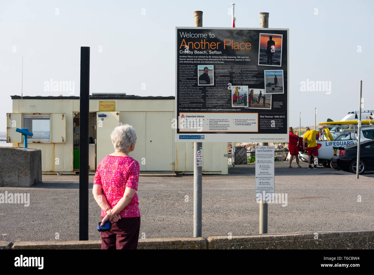 Signora anziana guardando le informazioni di segno di Antony Gormley è un altro posto spiaggia installazione artistica Foto Stock