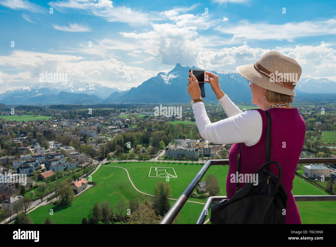 Donna Senior Travel, la vista di una donna senior di scattare una foto con uno smartphone di una scena lansdcape con montagne di Salisburgo, Austria. Foto Stock