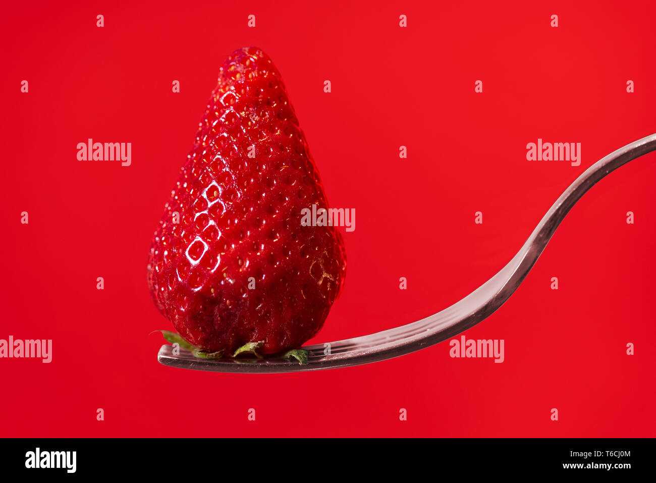 Fragola rossa sulla forcella con display rosso sfondo Foto Stock