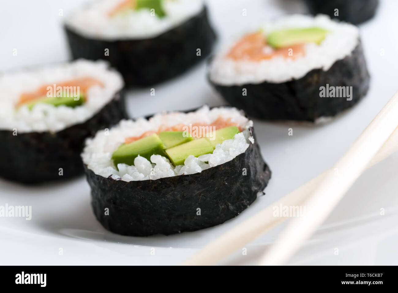 Rotoli di Sushi con salmone, avocado, riso nelle alghe marine e bastoncini su una piastra. Foto Stock