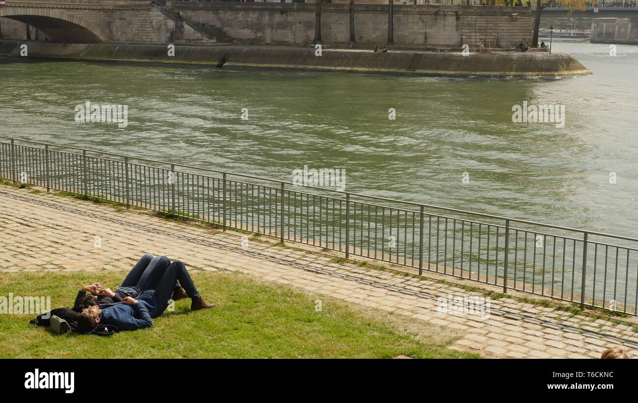 Una coppia romantica giacciono sull'erba al sole sulle rive del fiume Senna a Parigi. Foto Stock