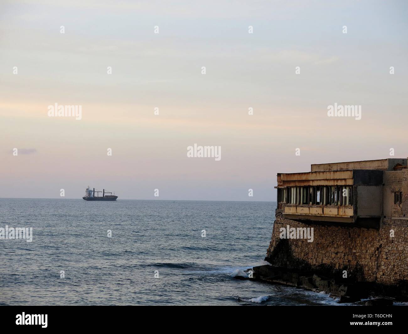 Il tramonto. Nave ancorata al largo e vecchio edificio fatiscente situato ad Heraklion, Creta, Grecia. Foto Stock