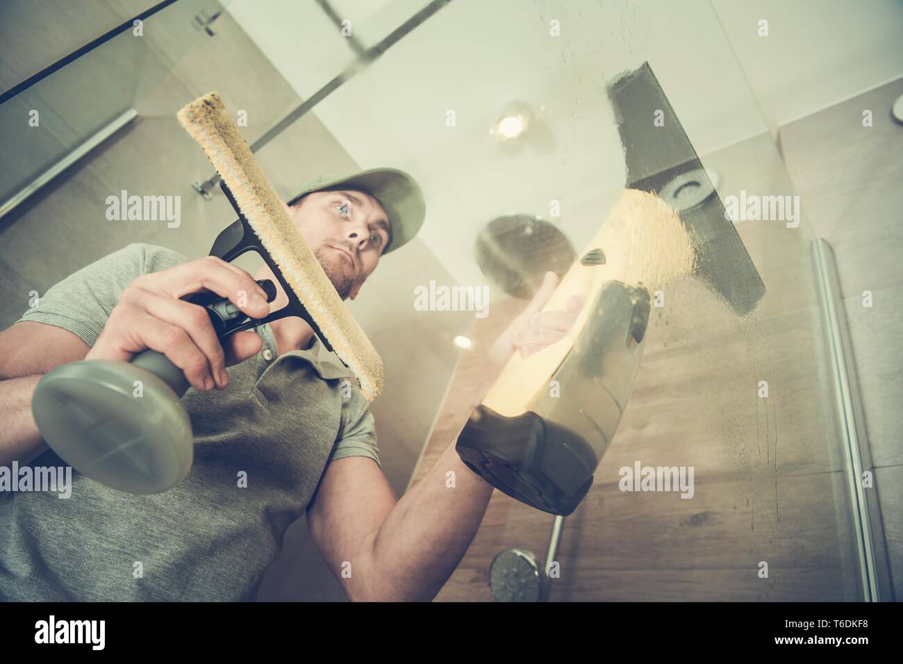 Bagno Cabina in vetro la pulizia. Uomini caucasici utilizzando Professional detergente per vetri. Foto Stock