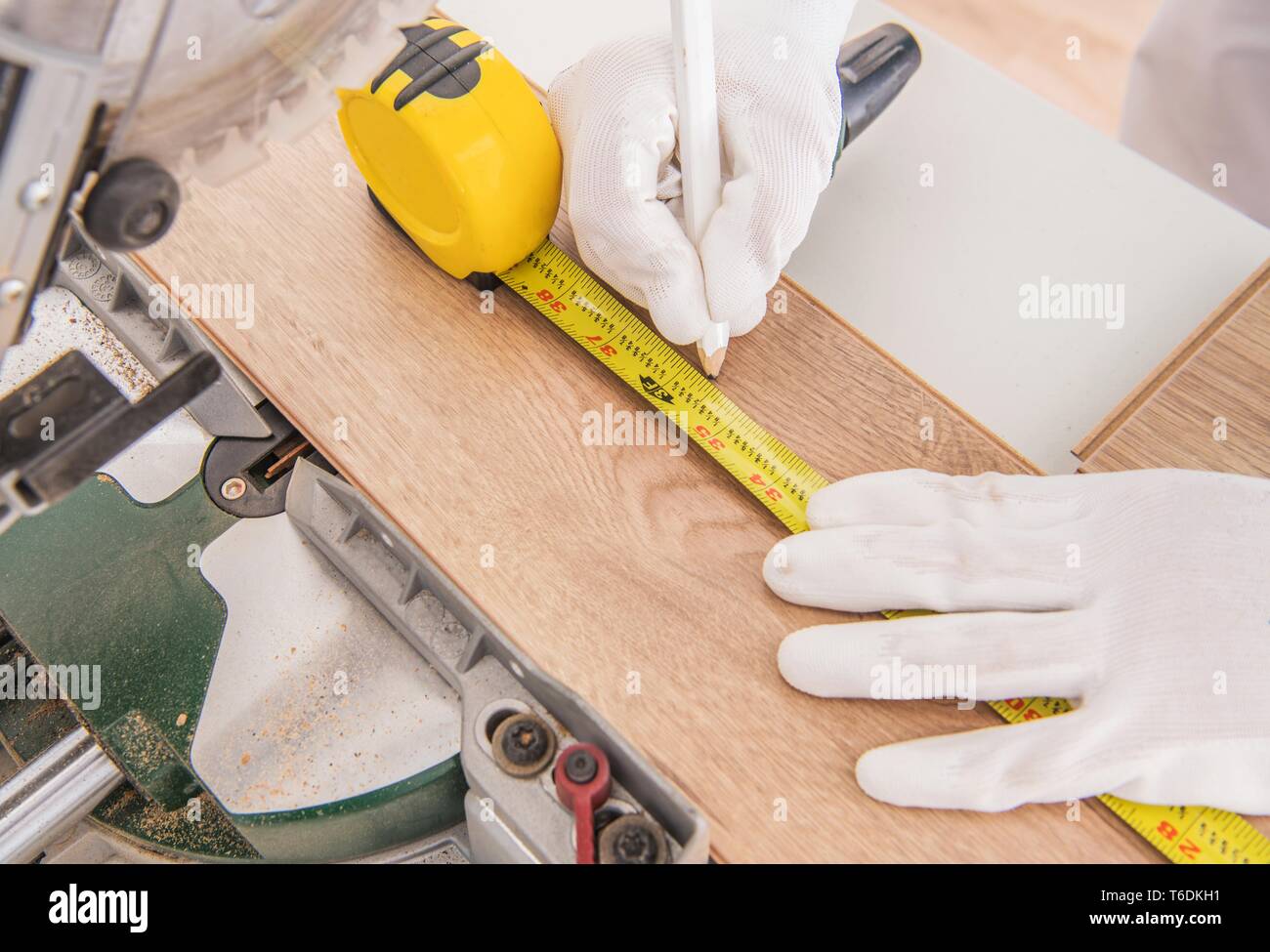 Operaio edile Misurare pezzo di legno laminato come pannello prima di tagliare con una sega circolare. Foto Stock