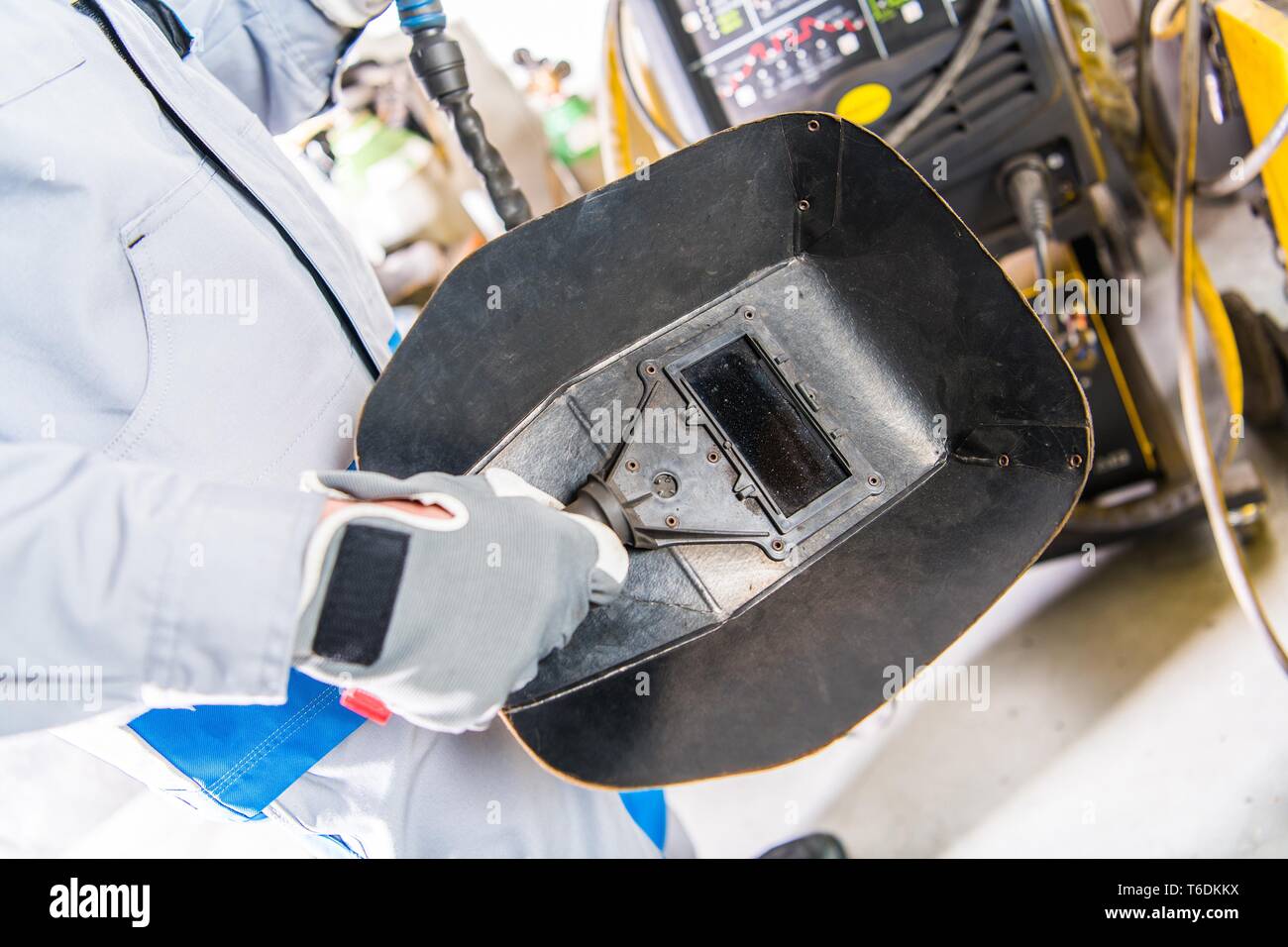 La maschera di saldatura in una mano. Saldatore e il suo equipaggiamento di sicurezza. Industria del metallo del tema. Foto Stock