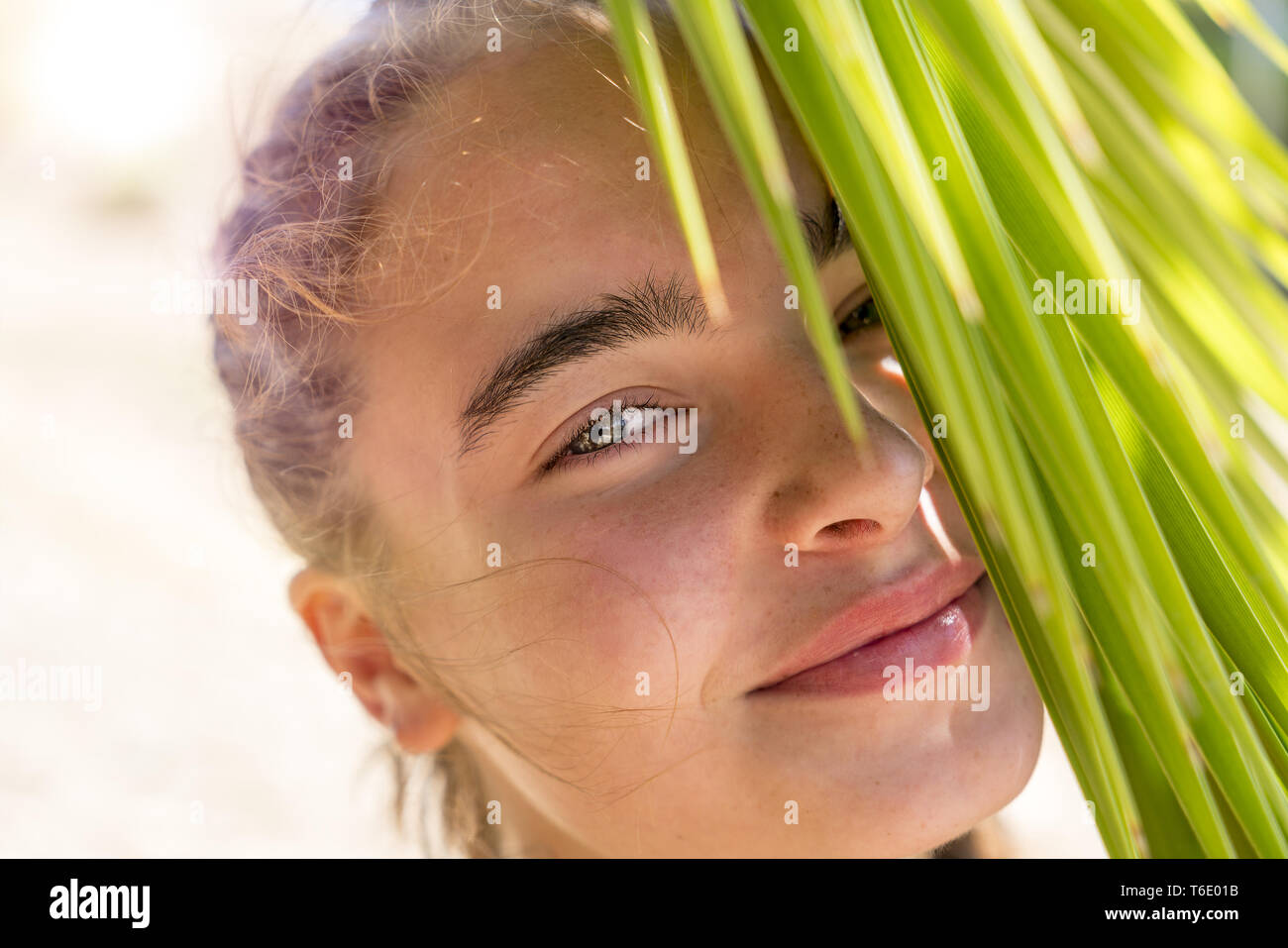 Ritratto di un sorridente giovane donna con Palm tree foglie Foto Stock