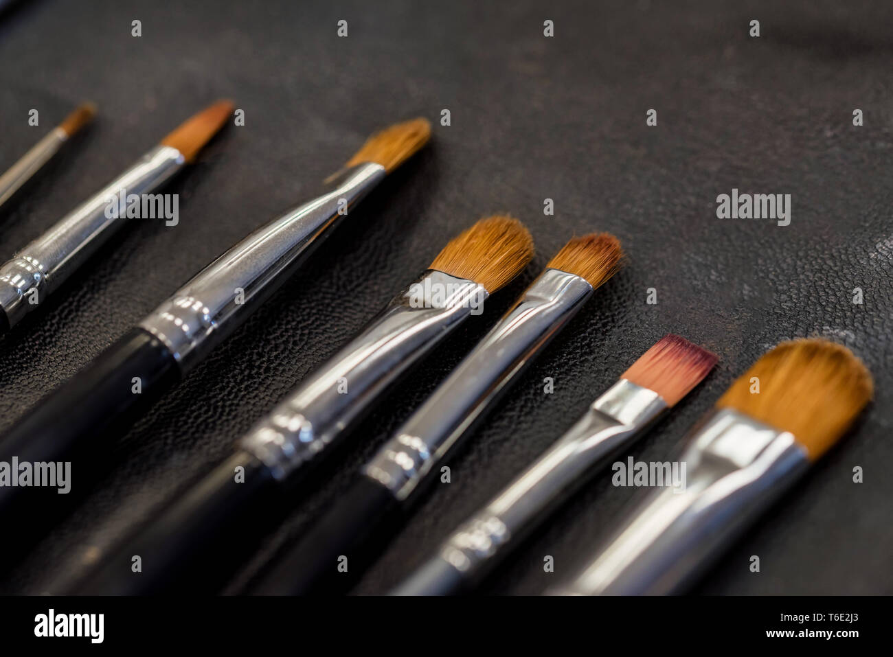 Set di pennelli per il trucco giacente sulla superficie scura vicino Foto Stock