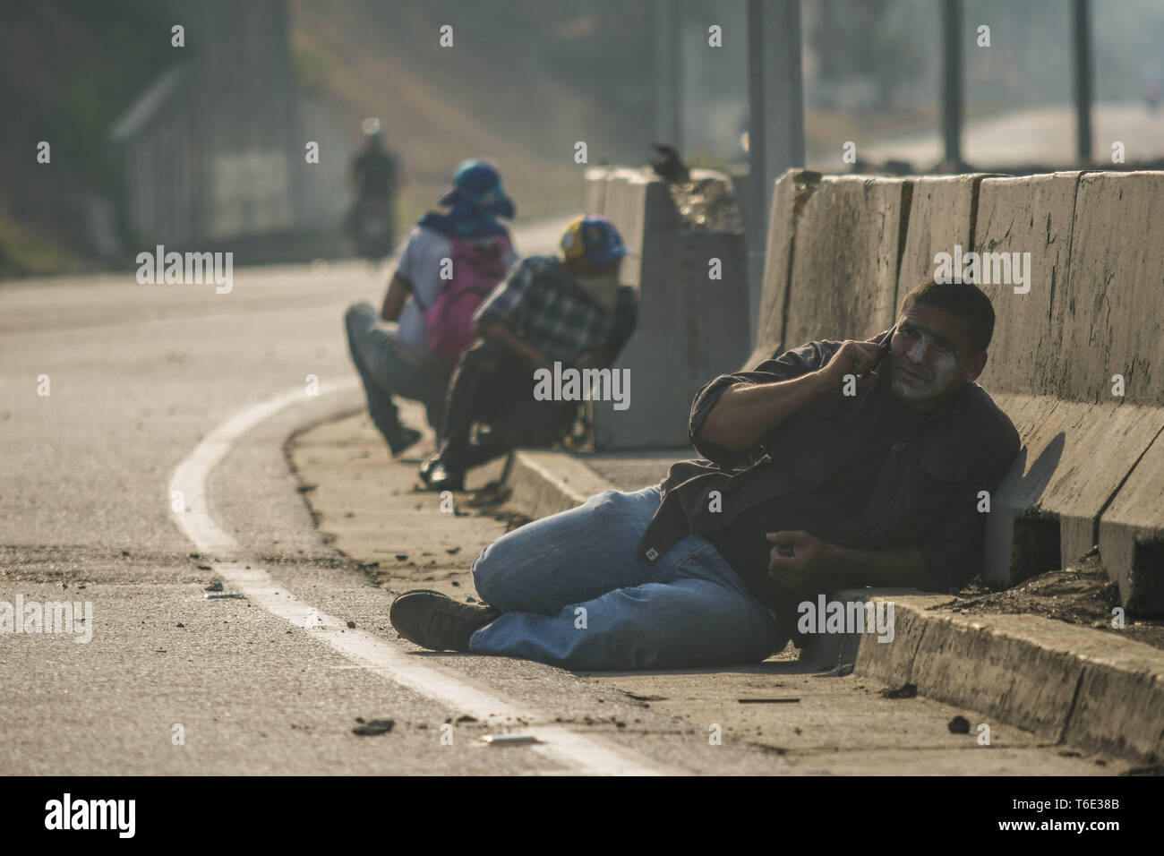 Manifestanti hanno visto scendere in basso sul terreno per evitare i proiettili. Militare venezuelano che sostengono il venezuelano leader dell opposizione Juan Guaido ha preso per la strada con le loro armi insieme con anti governo manifestanti in un colpo di stato militare contro il governo socialista guidato da presidente Nicolas Maduro. Foto Stock