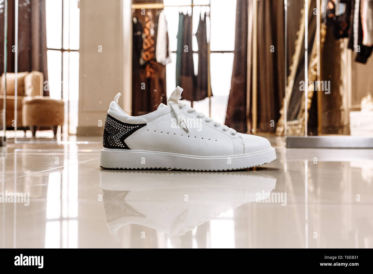 Bianco elegante sneaker con un ornamento stella fatta di pietre strass sullo sfondo sul pavimento chiaro Foto Stock